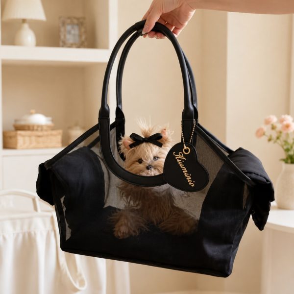 Black mesh pet carrier tote held by its handles with a small dog visible inside.