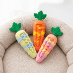Carrot shaped dog chew toy in three pastel and orange colors arranged on a pet bed.