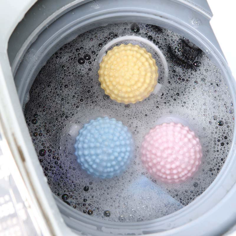 Floating laundry lint and pet hair catcher in blue, pink and yellow floating in wash water.