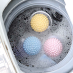Floating laundry lint and pet hair catcher in blue, pink and yellow floating in wash water.