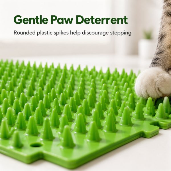 Green cat deterrent mat closeup of rounded plastic spikes beside a cat's paw.