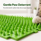 Green cat deterrent mat closeup of rounded plastic spikes beside a cat's paw.