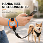 Orange and blue wrist dog leash on a wrist while the wearer holds a phone.